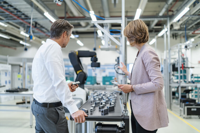 Businessman and businesswoman talking in a modern factory hall Image description